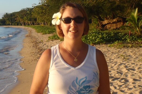 Woman with flower on sunny beach.
