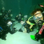 Group of scuba divers underwater in pool session.