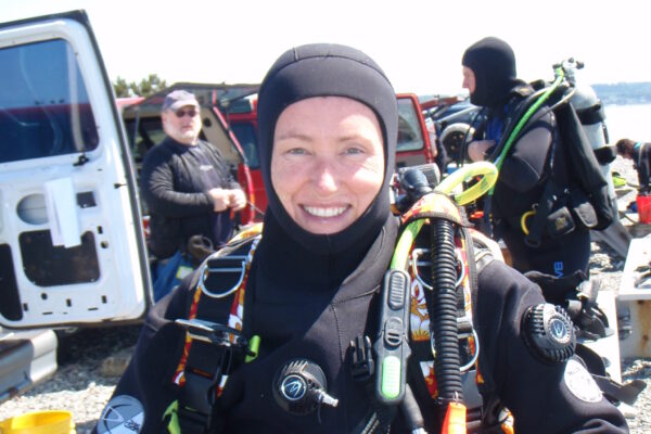 Smiling scuba diver preparing for a dive on land.