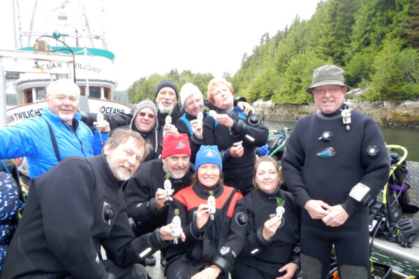 Group of divers posing on boat with figurines.