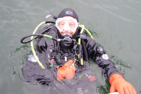 Scuba diver in water wearing diving suit and gear.