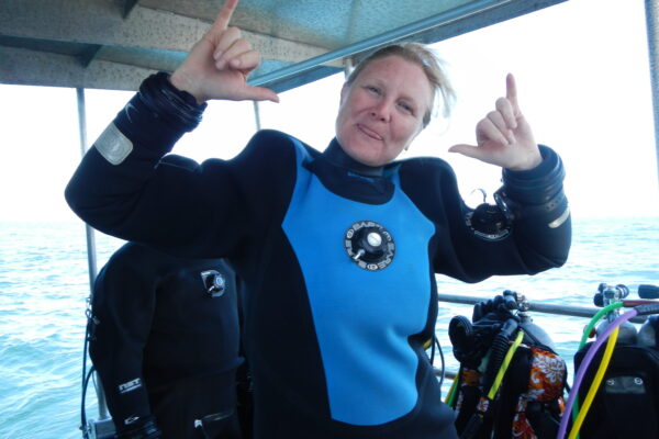 Smiling diver in blue wetsuit on boat.