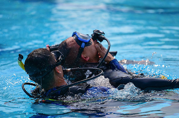 Scuba diver practicing rescue in pool.