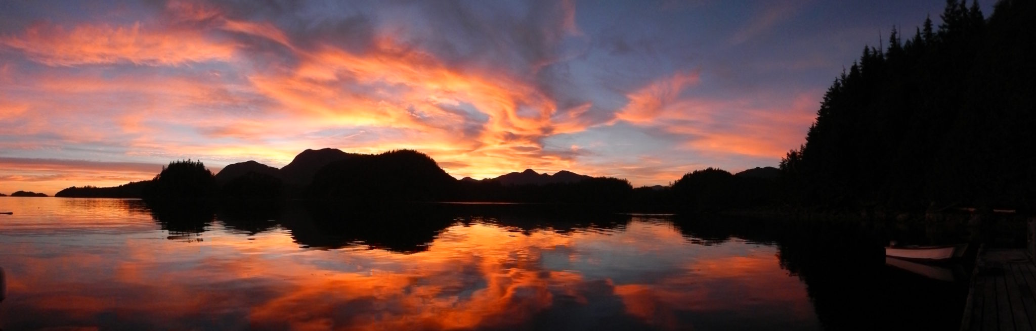 Dramatic sunset over calm lake with reflections.