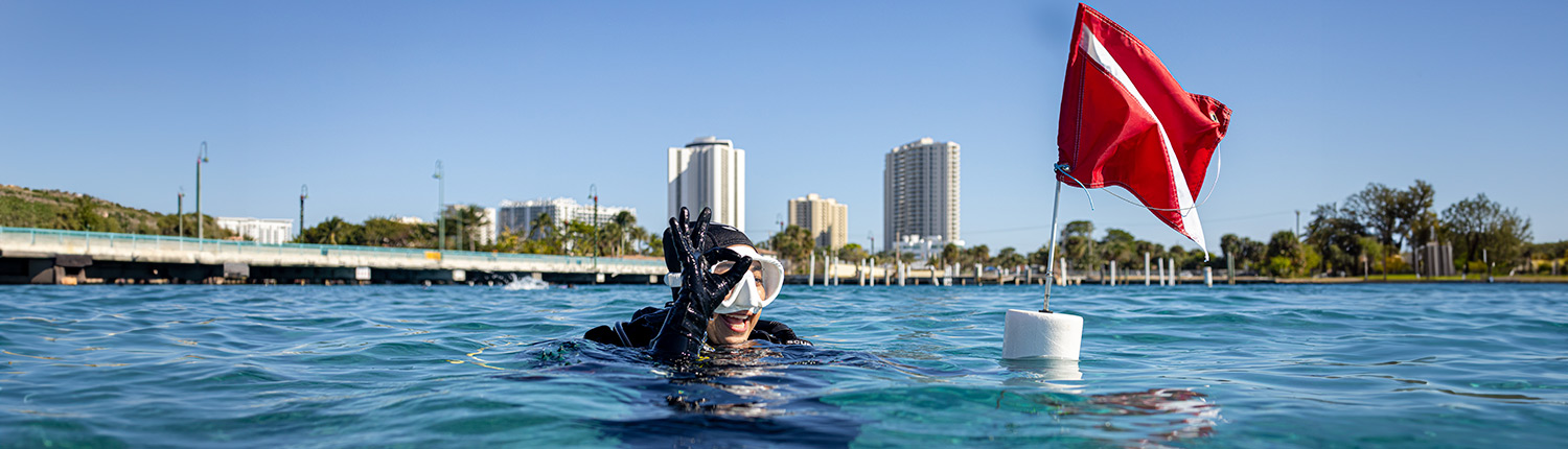 Diver in water with red safety flag nearby