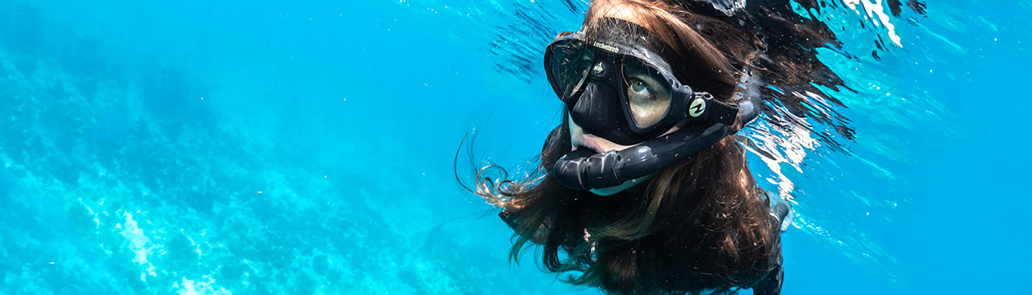 Woman snorkeling underwater in clear blue sea