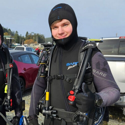 Smiling diver in wetsuit with scuba gear.