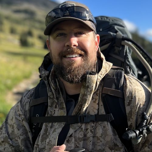 Smiling man hiking in camouflage gear outdoors