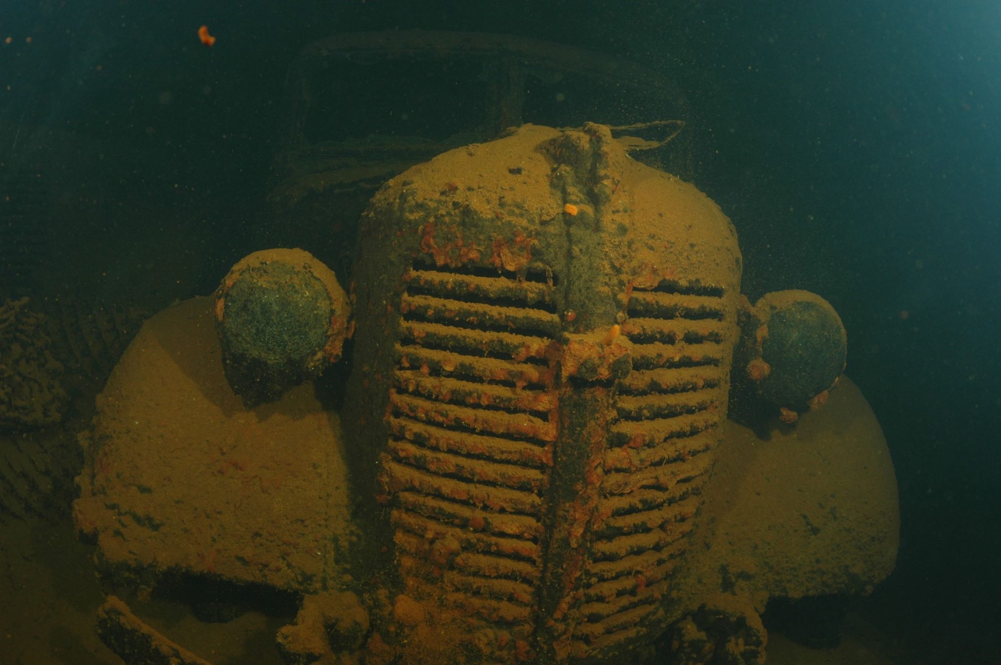 Rusty vintage car submerged underwater.