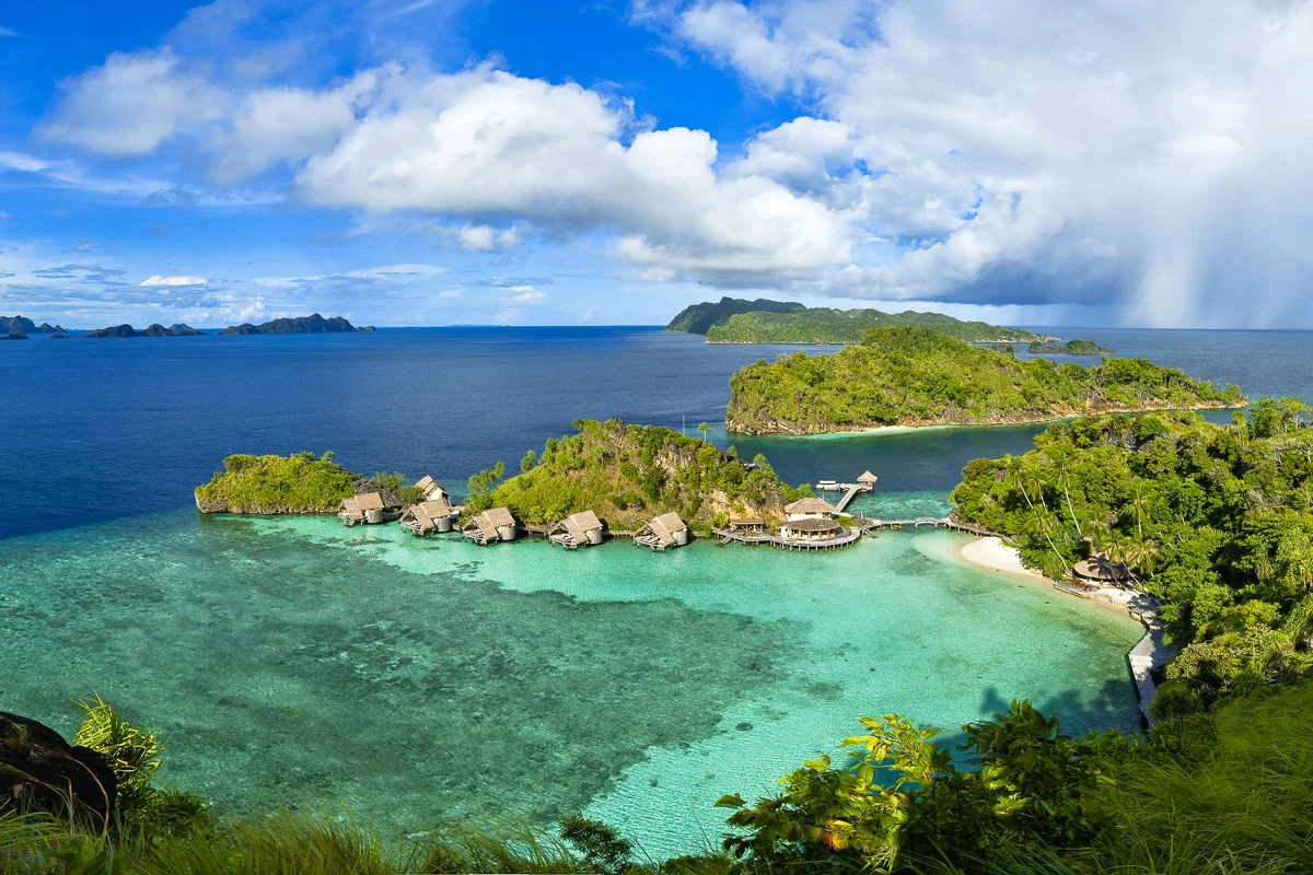 Tropical island resort with overwater bungalows and greenery.